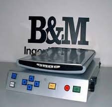 Silver document scanner on top of a larger rectangular box with control buttons.