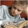 Picture of a boy in a white shirt reading a book with his left elbow on a surface and his left hand holding up his head. With his right hand, he holds the book open.