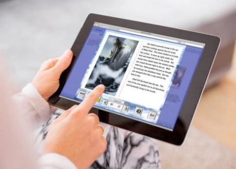 Partial view of woman holding a tablet with left hand and right hand is pointing at text on the screen.