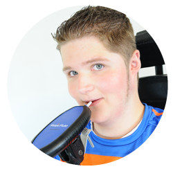 Picture of a teenage boy's head and shoulders blowing into a tube connected to an oblong black device.
