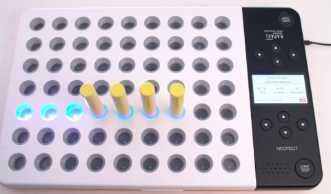 A 9x7 grid of peg holes in a whiteboard that has a cord attached on the upper right side. Seven of the holes have a neon blue light that is on, and 4 of those holes have long yellow pegs in them. The right side of the board has a narrow strip which is black and has two sets of buttons, each set for a person sitting on either side of the board. These buttons are labeled with directional arrows. There is also a speaker on both sides, and a button in each of the two corners labeled "start/stop".