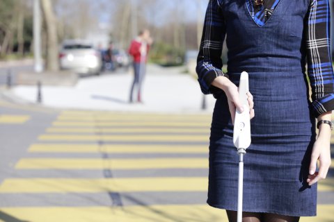 A person walking down a street with a white that has a long handle with menu options.