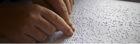 Close-up of hands reading braille with two index fingers.