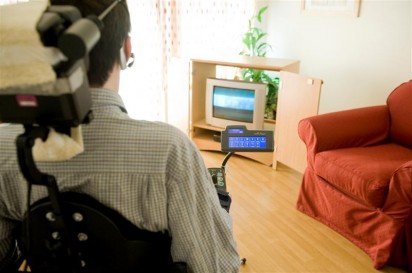 From the perspective of an individual watching television. Remote control is in the foreground, the Primo! Environmental Control Unit is in the middle ground, and television is in the background. 