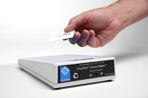 Inclined rectangular pad with view of controls and ports on black panel for connecting cables along with a hand holding a white soundtag.