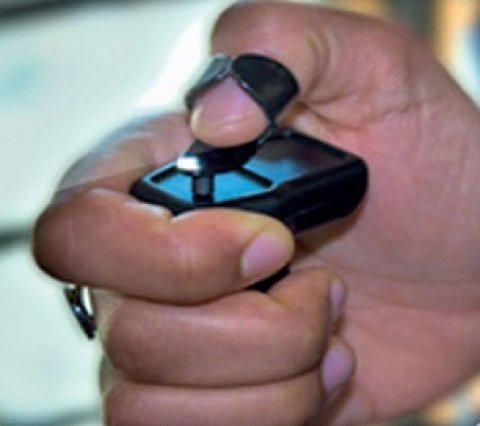 A small device wrapped by the index finger and with a loop at the top and a thumb through the loop.