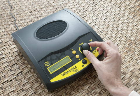 A small box-shaped device with a small display panel, four simple buttons, and a large knob dial. 