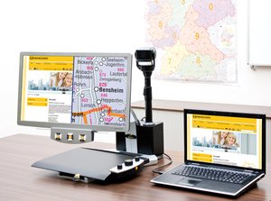 Medium-sized monitor with a connected platform underneath at its base. The platform allows materials to be placed and magnified. On the bottom front edge of the monitor, there are three round knobs. A laptop and external camera are both connected. The camera is facing a classroom wall.