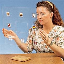 Woman sitting at a table holding transparent board with image overlays.