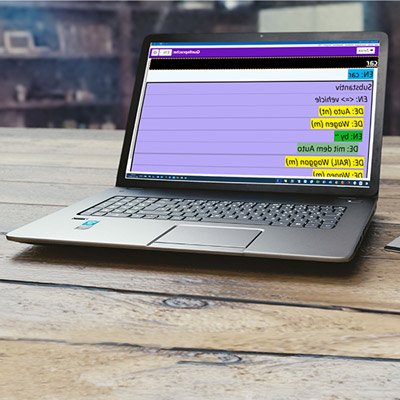 A laptop sitting on a wooden table displaying a dictionary entry in high-contrast, purple, yellow, and green display.