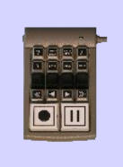 A small black device with several media play buttons, such as skip forward, skip back, play, and pause, resembling a TV remote.