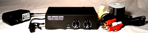 A medium-sized, black, and rectangular device, with two round dials on the front, is sown next to various input/output cords, a smaller black box, a spool of cord, and other electrical components.