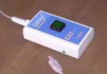 Rectangular white box housing a blue rectangular box with a green button on top and cord attached to the top of its short side. 