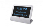 A white rectangular device with a black background and large blue text displaying the time, day, time of day, and date.
