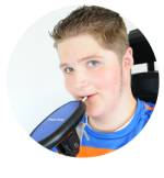 Picture of a teenage boy's head and shoulders blowing into a tube connected to an oblong black device.