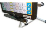 The bottom half of a tablet that is mounted on a tabletop stand with a wide but slim rectangular eye-tracking device attached to its bottom edge. The tracking device has a small green light in its center. The tablet has a USB cord plugged into it. 