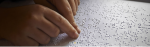 Close-up of hands reading braille with two index fingers.