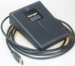 A gray foot pedal with a USB connecting cable and anti-slip texture on its face.