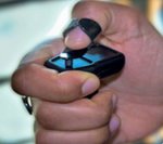 A small device wrapped by the index finger and with a loop at the top and a thumb through the loop.