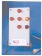 A rectangular device with six lightbulbs in a cross shape with one on. In the lower right corner, there is an attached cord and connector.