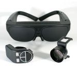 Large, black set of goggles worn over the head. A small camera lens and another component sit in front.