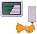 Small rectangular speaker output device on left and small, white handheld device with one button on right, attached to a yellow cord.