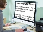 A woman uses a Mac desktop computer, which is displaying high-contrast, black-on-white, magnified content.